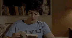 gif of a guy suddenly grasping his head before standing up, stumbling in agony before ripping off his shirt and removing his pants, underwear included